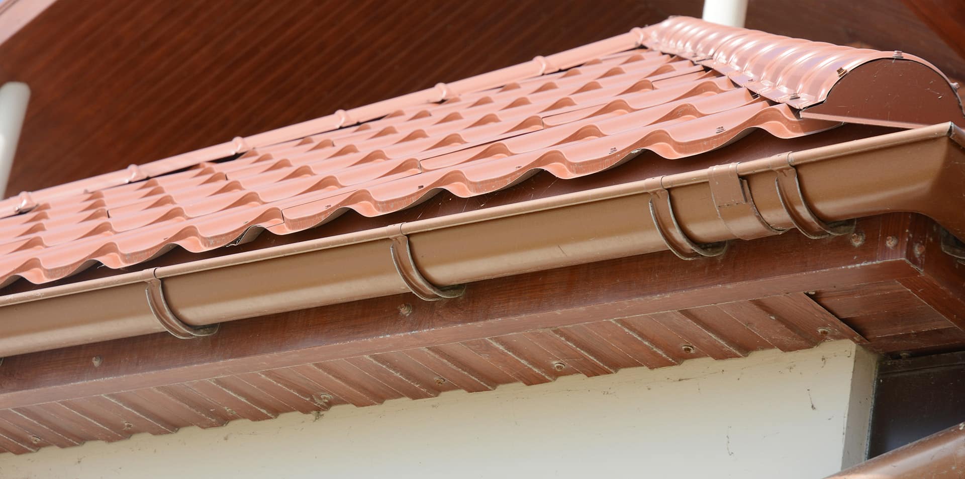 A close up on red metal tile rooftop with wood soffit, house eaves