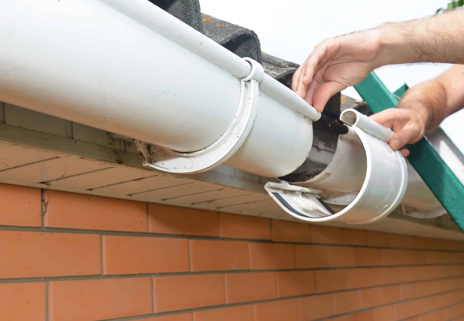 Roof gutter installation and repair. A man on a ladder is replac