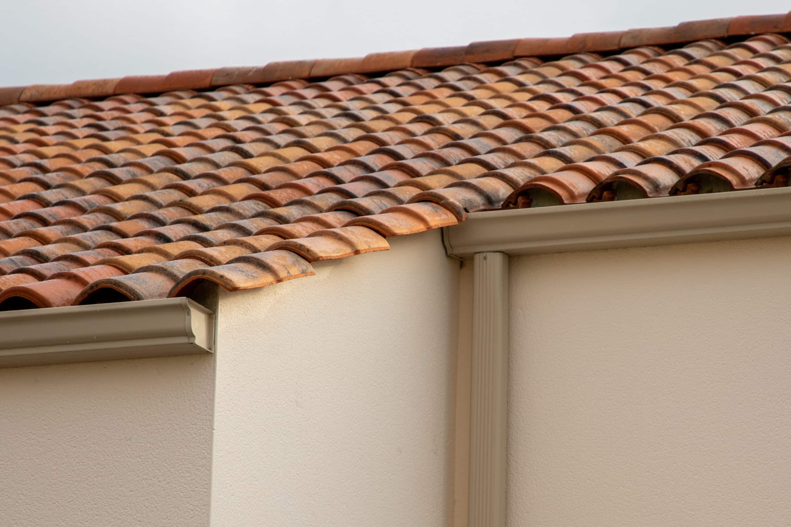 metal brown gutter on home facade beige roof covered with ceramic tiles Close up